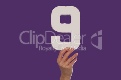Female hand holding up the number 9   from the top