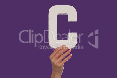 Female hand holding up the letter C from the bottom