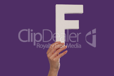 Female hand holding up the letter F from the bottom