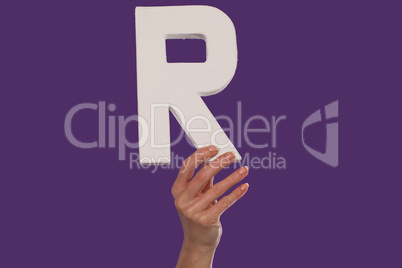 Female hand holding up the letter R from the bottom