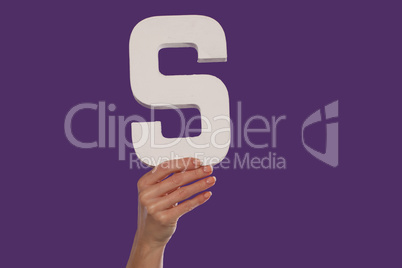 Female hand holding up the letter S from the bottom