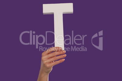 Female hand holding up the letter T from the bottom