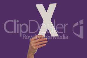 Female hand holding up the letter x from the bottom