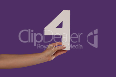 Female hand holding up the number 4 from the left