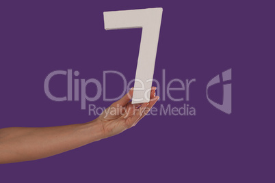 Female hand holding up the number 7 from the left