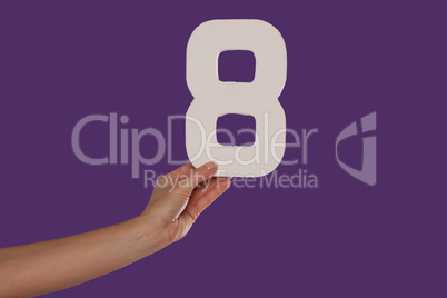 Female hand holding up the number 8 from the left