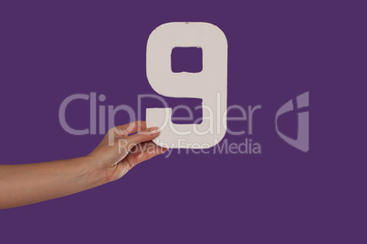 Female hand holding up the number 9 from the left