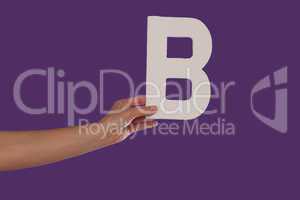 Female hand holding up the letter B from the left