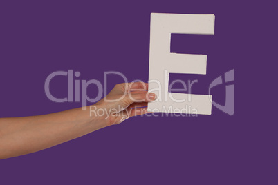 Female hand holding up the letter E from the left