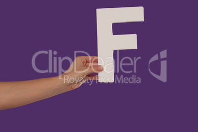 Female hand holding up the letter F from the left