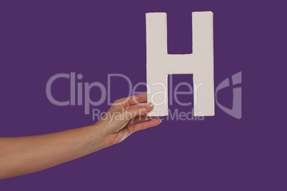 Female hand holding up the letter H from the left