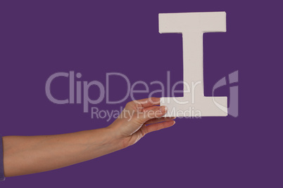 Female hand holding up the letter I from the left