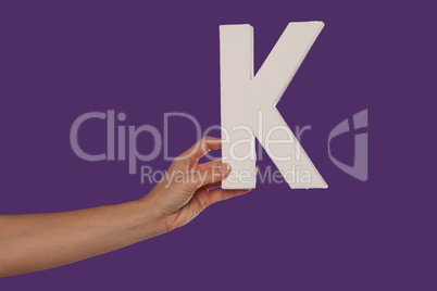 Female hand holding up the letter K from the left