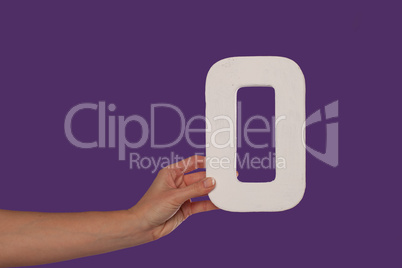 Female hand holding up the letter O from the left