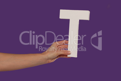 Female hand holding up the letter T from the left