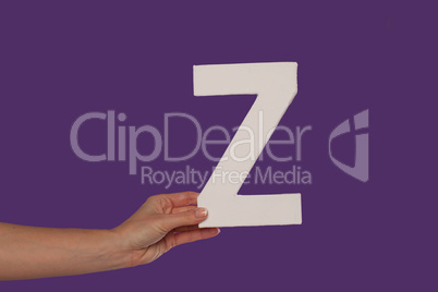 Female hand holding up the letter Z from the left