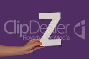 Female hand holding up the letter Z from the left