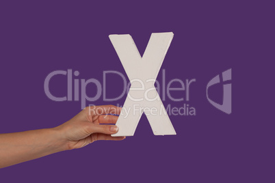 Female hand holding up the letter X from the left