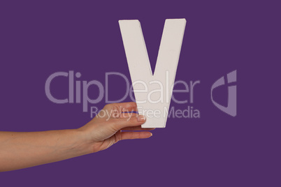 Female hand holding up the letter V from the left
