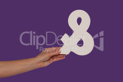 Female hand holding up an ampersand from the left