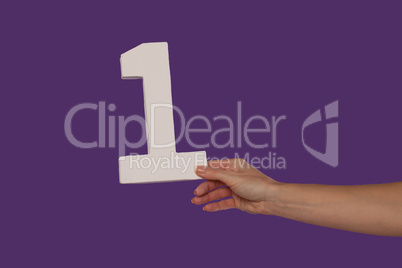 Female hand holding up the number 1 from the right