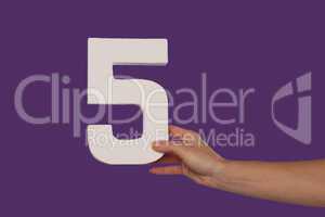 Female hand holding up the number 5 from the right