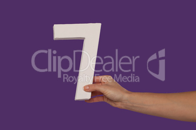 Female hand holding up the number 7 from the right
