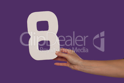 Female hand holding up the number 8 from the right