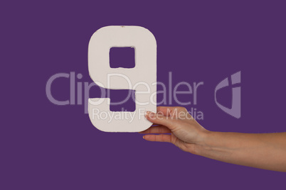 Female hand holding up the number 9 from the right