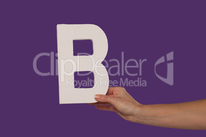 Female hand holding up the letter B from the right