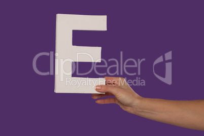 Female hand holding up the letter E from the right