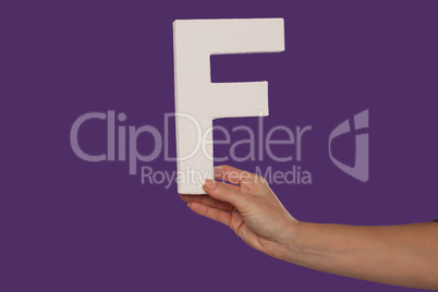 Female hand holding up the letter F from the right
