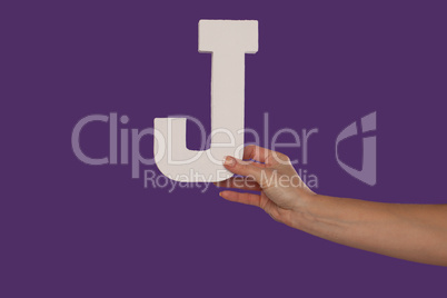 Female hand holding up the letter J from the right