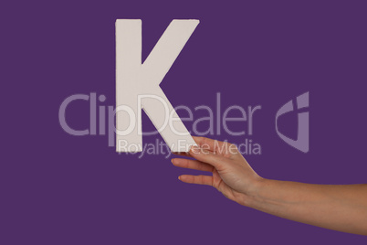 Female hand holding up the letter K from the right