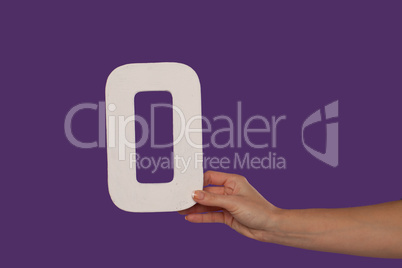 Female hand holding up the letter O from the right