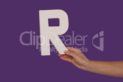 Female hand holding up the letter R from the right