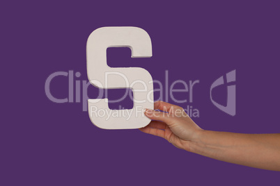 Female hand holding up the letter S from the right