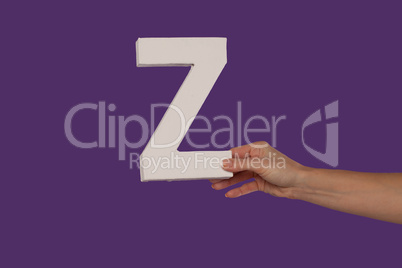 Female hand holding up the letter Z from the right