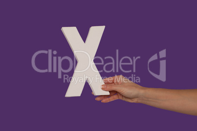 Female hand holding up the letter X from the right