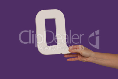 Female hand holding up the letter Q from the right