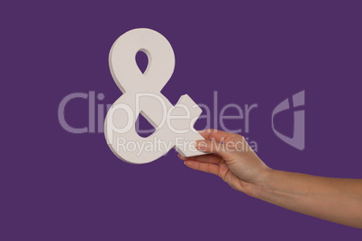 Female hand holding up an ampersand from the right