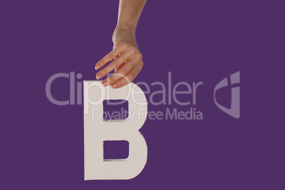 Female hand holding up the letter B from top