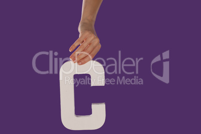 Female hand holding up the letter C from top