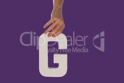 Female hand holding up the letter G from top