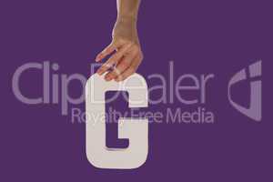Female hand holding up the letter G from top
