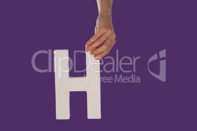 Female hand holding up the letter H from top