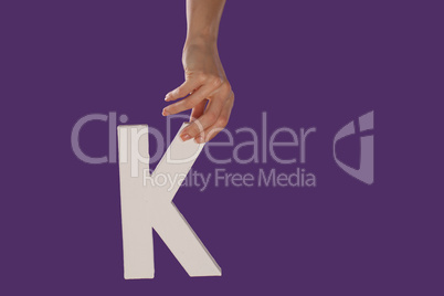 Female hand holding up the letter K from top