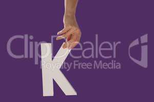 Female hand holding up the letter K from top