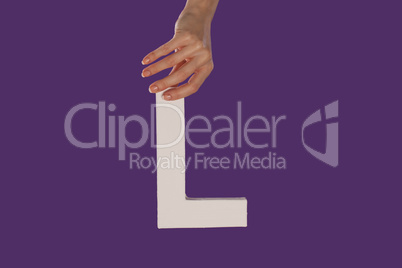 Female hand holding up the letter L from top