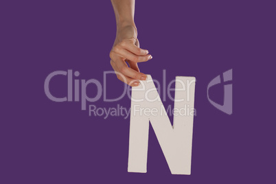 Female hand holding up the letter N from top